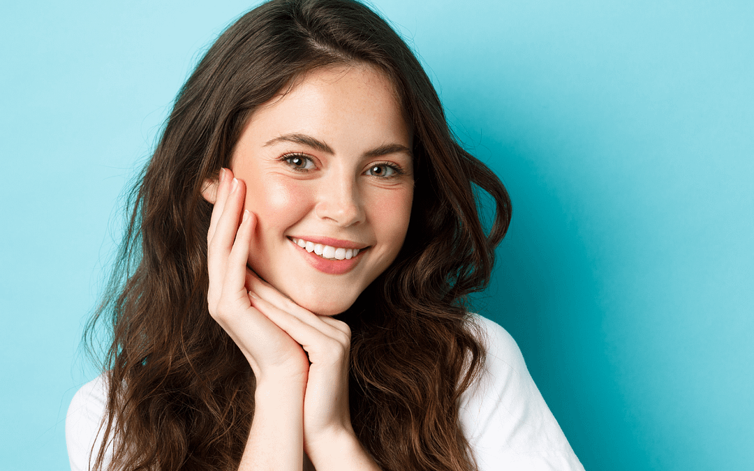 Brunette female smiling at camera hands under chin